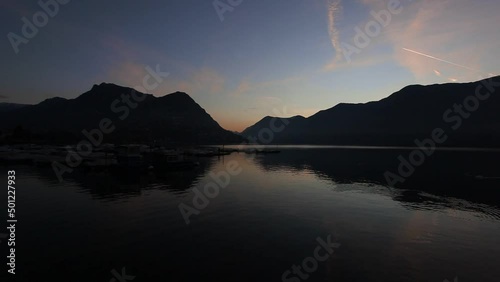 Sunrise on the lugano lake with mountains reflections on placid waters. Ticino, Switzerland