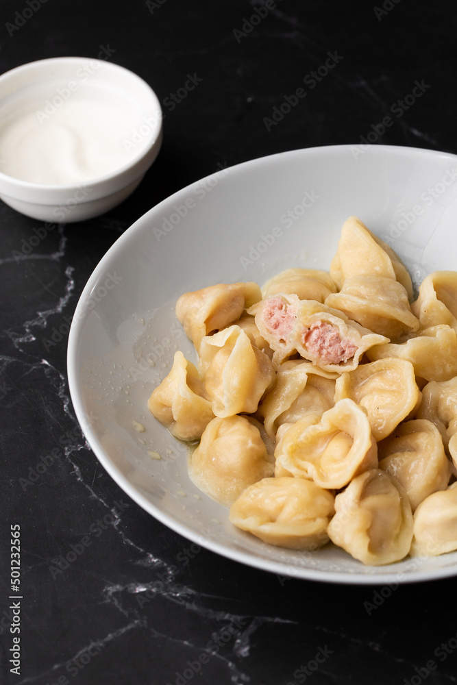 Meat dumplings, homemade russian pelmeni in bowl isolated on black background with clipping path