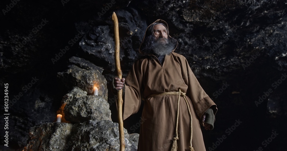 Fototapeta premium Elderly sorcerer standing inside cave