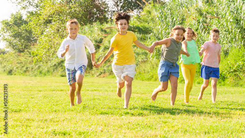 Group of five happy children who are jogging in a park on a sunny day