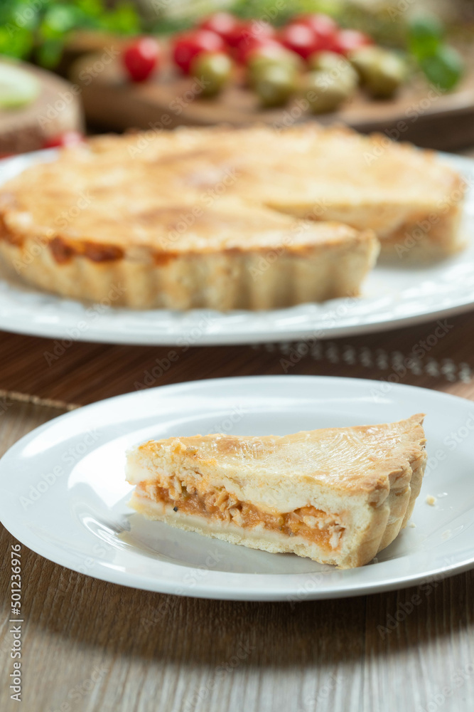 Close up piece of Chicken pie with cottage cheese, tomatoes, onion and olives on wooden table and white plate.