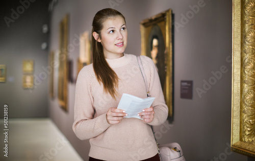 Portrait of young woman with guide looking at pictures in a museum of the arts