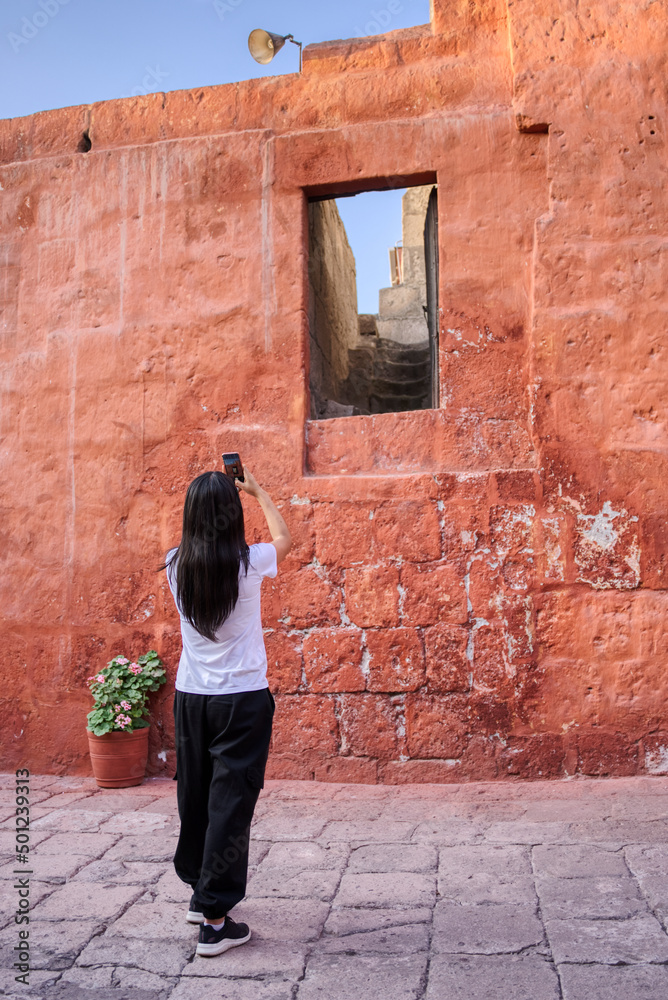 Turista latina fotografiando una ventana extraña de la calle Málaga en el monasterio Santa Catalina en Arequipa