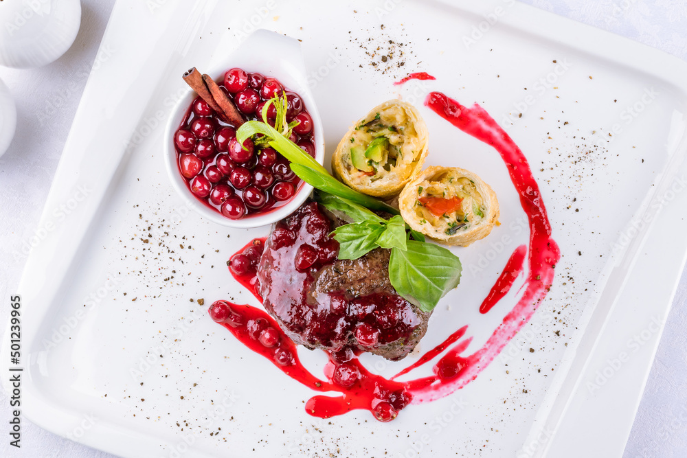 Venison steak with lingonberry sauce on a white plate top view Venison steak with lingonberry sauce on a white plate top view