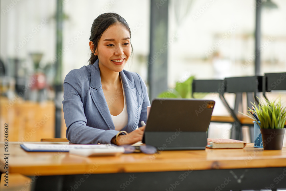 Good looking young Asian woman in pants jacket and tie working with documents in the office Good looking young Asian woman in pants jacket and tie working with documents in the office