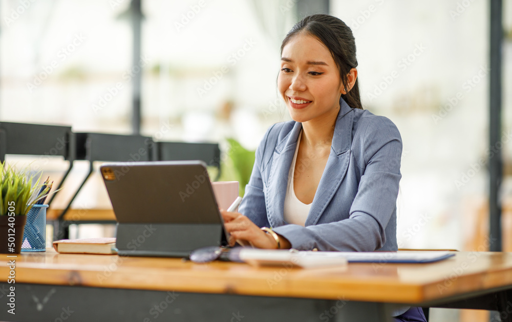 Good looking young Asian woman in pants jacket and tie working with documents in the office Good looking young Asian woman in pants jacket and tie working with documents in the office