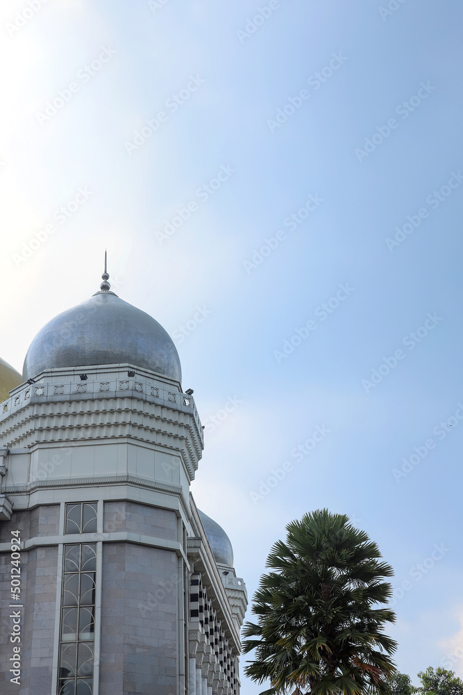 Silver mosque dome and palm tree  under the blue sky