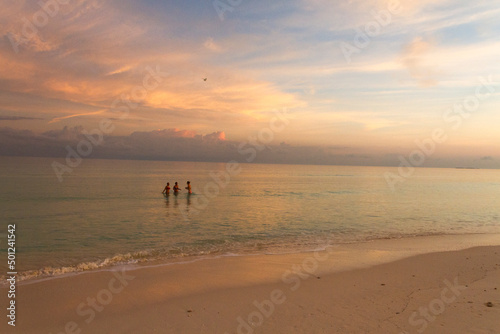 Gente bañándose en la playa al atardecer