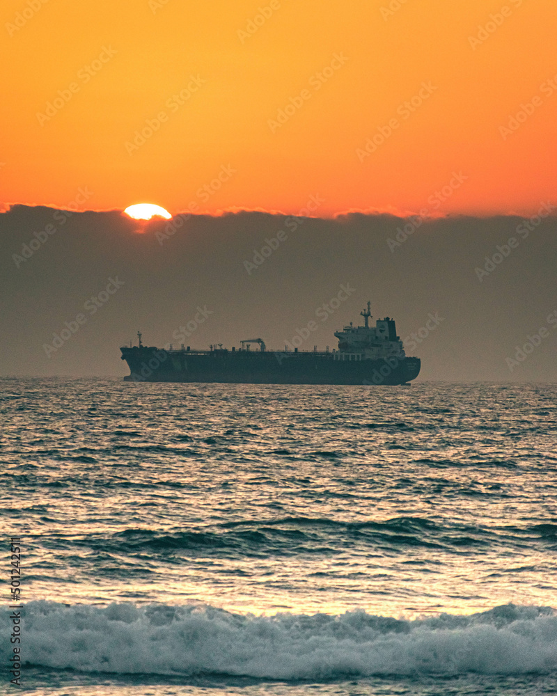 Cargo ship at the sunset in Santo Domingo, Chile.
You can see the sun hiding behind the clouds at the horizon