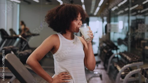 Attractive fitness African American woman finishing workout and drinking protein milk shake vitamins after training. Bodybuilding. Healthy lifestyle.