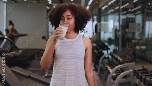 Attractive fitness African American woman finishing workout and drinking protein milk shake vitamins after training. Bodybuilding. Healthy lifestyle.