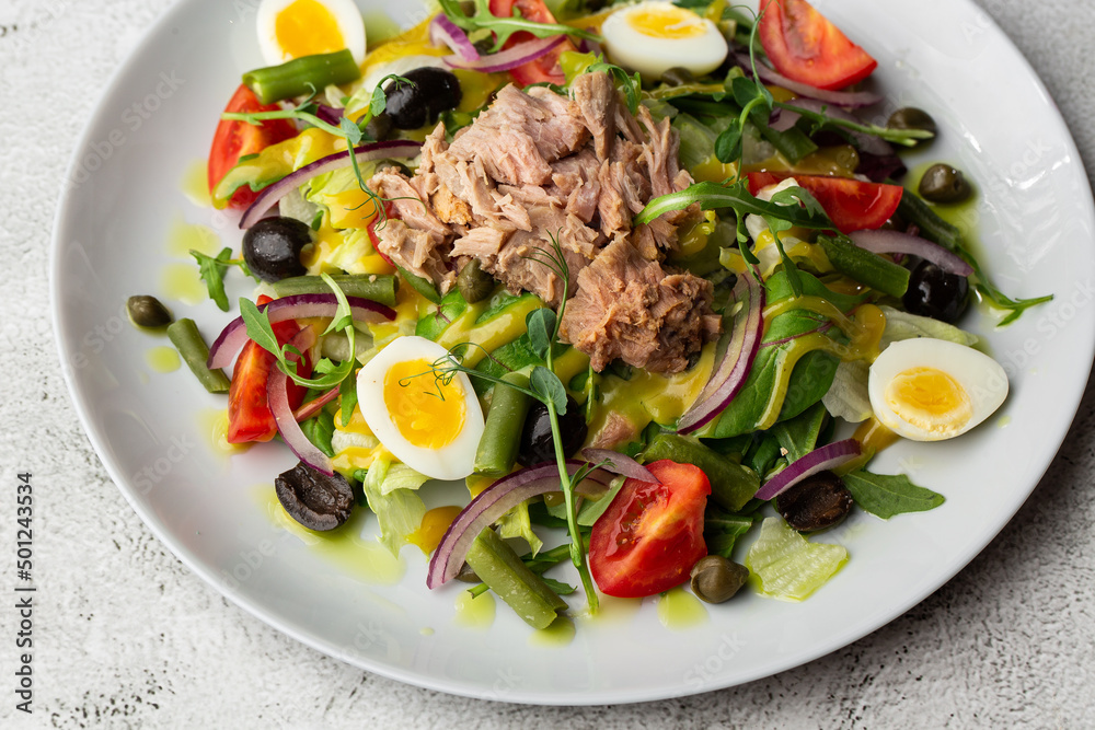 French salad Nicoise with tuna, egg, green beans, tomatoes, olives, lettuce, onions and anchovies on a white background. Healthy food French salad Nicoise with tuna, egg, green beans, tomatoes, olives, lettuce, onions and anchovies on a white background. Healthy food
