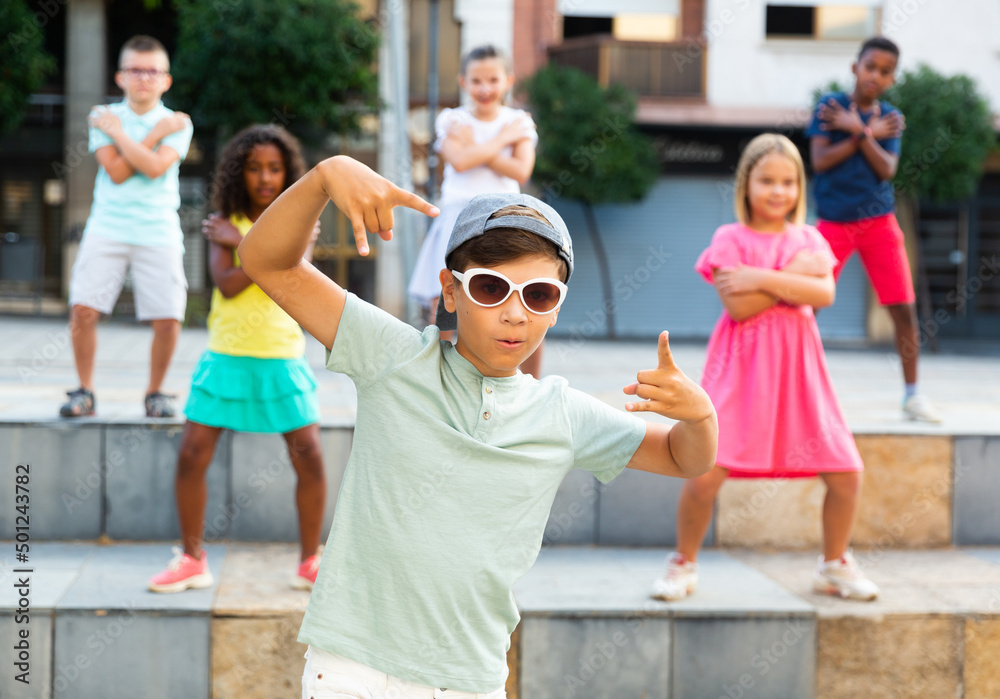 Children exercising contemporary dance moves during their outdoor rehearsal.