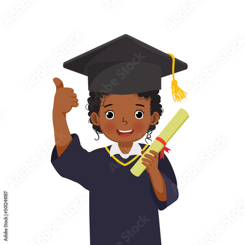 cute little African schoolgirl in graduation hat and gown holding diploma certificate showing thumb up