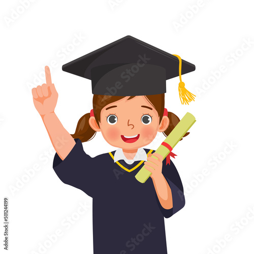 cute little schoolgirl in graduation hat and gown holding diploma certificate pointing finger up