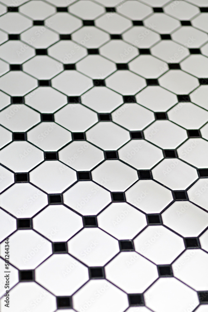 White and black ceramic tiles floor background, view from above. Selective focus image. White and black ceramic tiles floor background, view from above. Selective focus image.