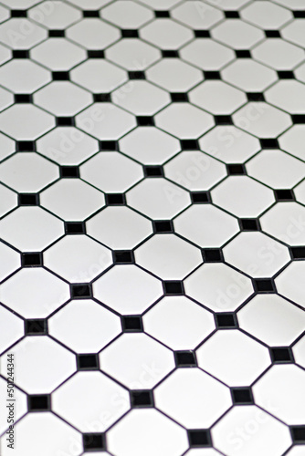 White and black ceramic tiles floor background  view from above. Selective focus image.