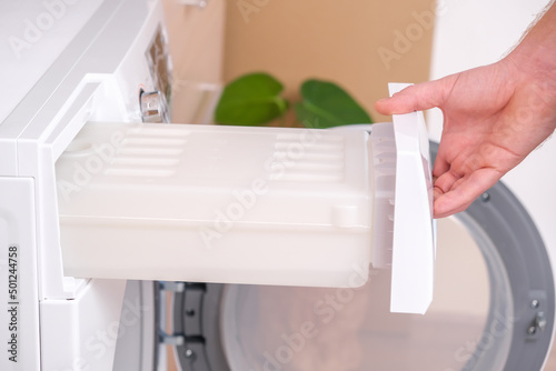 A man takes out a container from the dryer to collect water squeezed out of wet laundry. photo