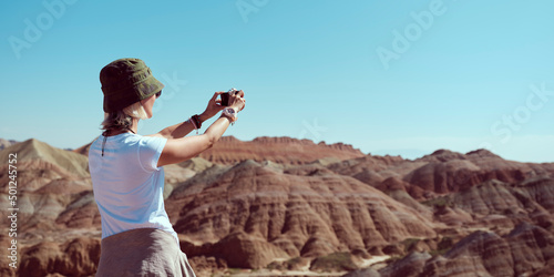rear view of asian female tourist taking a photo in geopark using cellphone photo