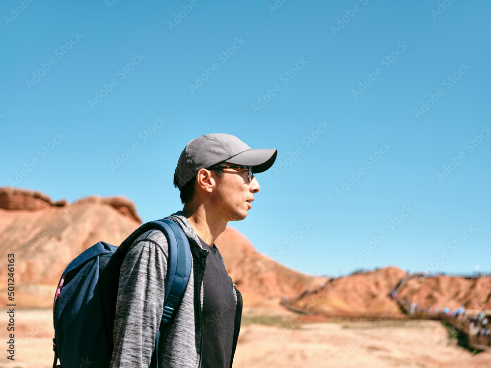 asian man walking in national park with yardang landforms