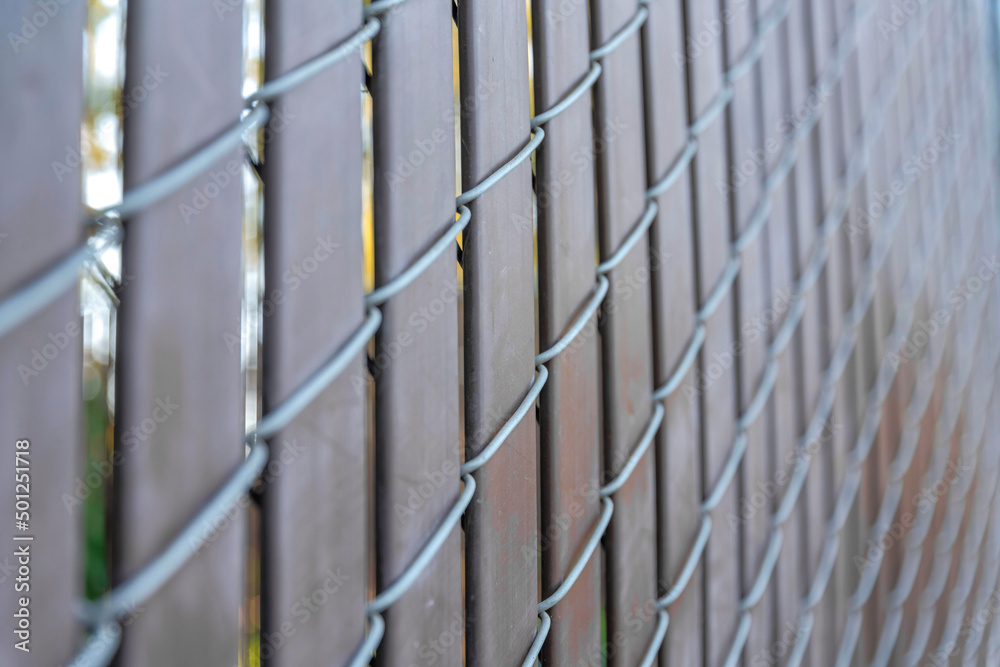 Selective focus of a chain link fence with brown privacy strips at Japanese Friendship Garden
