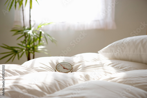 朝日の中のベッドと目覚まし時計