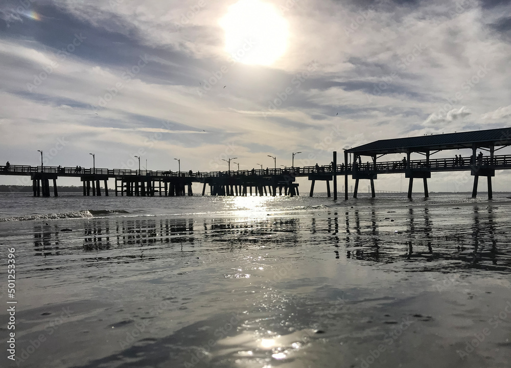 Silvery sunset highlighting an ocean pier.