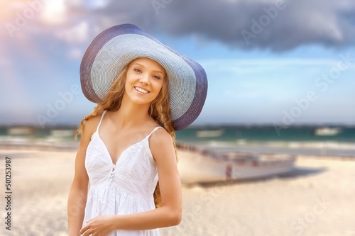 Beautiful woman with straw hat standing at beach. Young woman on vacation enjoy sea.