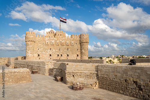 The Citadel of Qaitbay or the Fort of Qaitbay is a 15th-century defensive fortress located on the Mediterranean sea coast. Ordinary people walk nearby photo