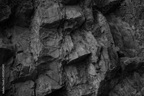 Black white rock texture. Rough mountain surface. Close-up. Volumetric stone background with space for design. Dark gray grunge backdrop.
