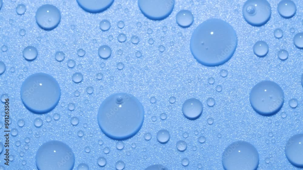 Close-up transparent water drops texture rotating on blue chroma key background Close-up transparent water drops texture rotating on blue chroma key background