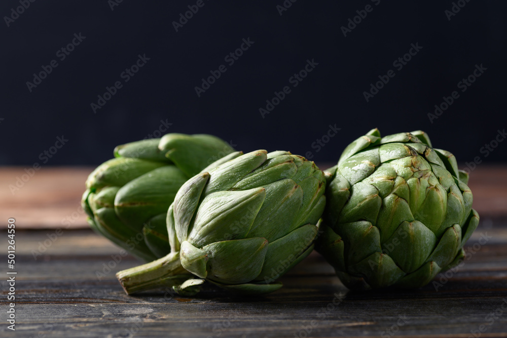 Fototapeta premium Green artichoke on wooden background, Edible flower bud