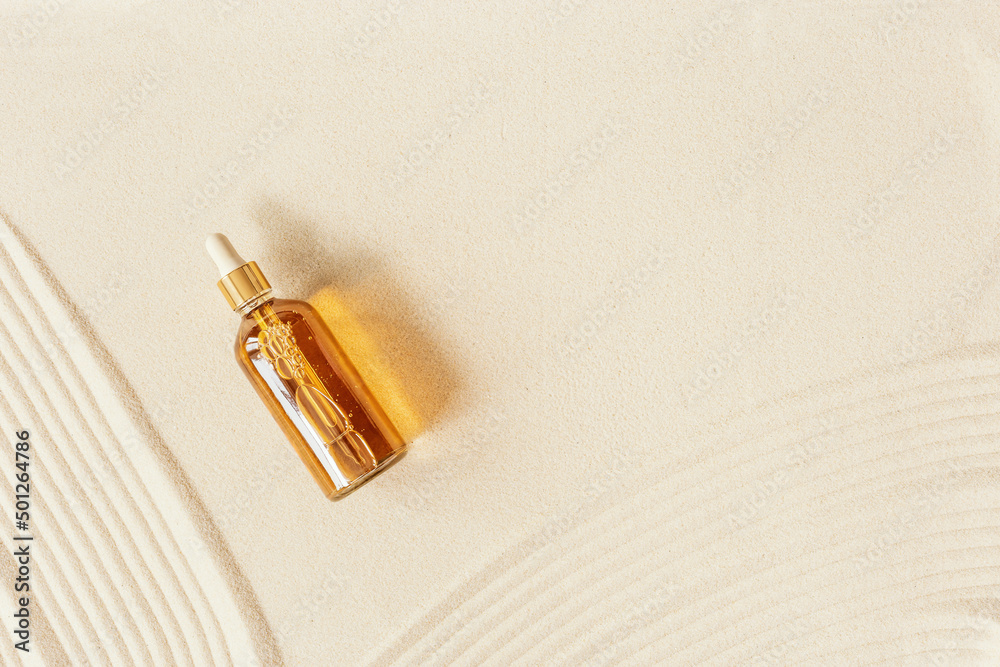 Liquid product package in glass bottle on fine sand. Hyaluronic or ...