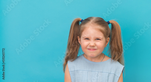 Foto Angry furious child grimacing make face over blue background.