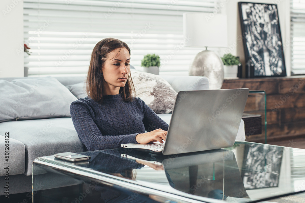 Woman entrepreneur working on laptop sitting at home Woman entrepreneur working on laptop sitting at home