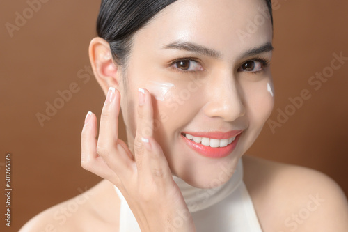 A young woman with beautiful face is holding cream , using cream of her face , beauty skin care concept