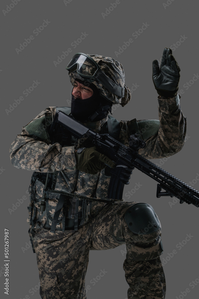 Portrait of attacking soldier equiped with modern uniform and weapon against gray background. Portrait of attacking soldier equiped with modern uniform and weapon against gray background.