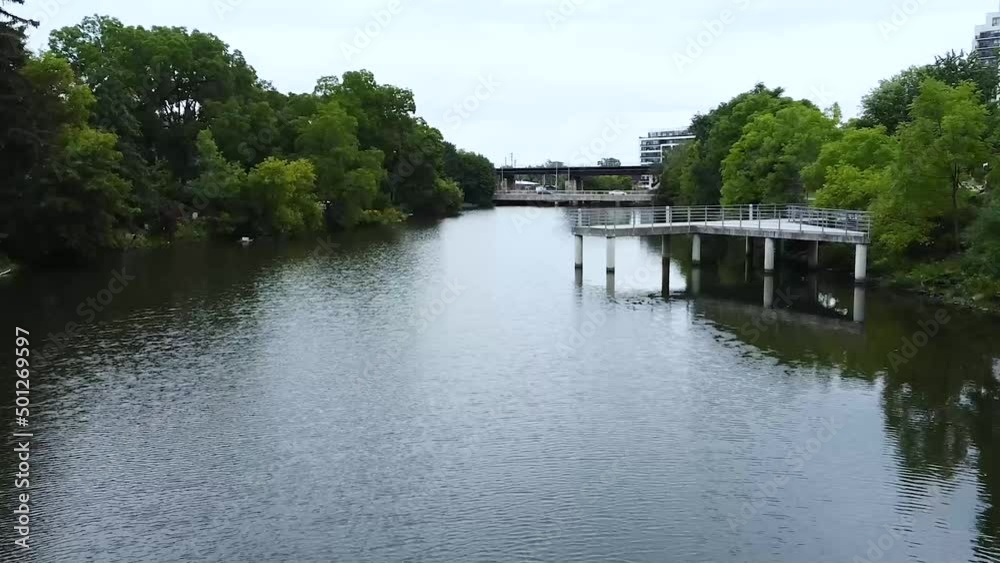 Low Drone Flying Through River Canal by White Docks and Water Birds with Train Tracks and Inner City Apartment Condos in Distance Low Drone Flying Through River Canal by White Docks and Water Birds with Train Tracks and Inner City Apartment Condos in Distance