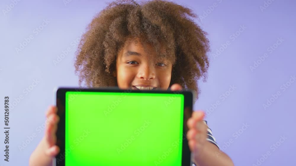 Studio Portrait Of Boy Using Digital Tablet With Green Screen Against Purple Background Studio Portrait Of Boy Using Digital Tablet With Green Screen Against Purple Background