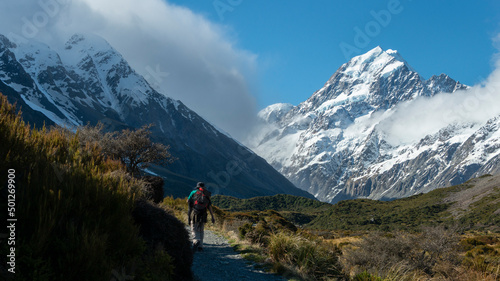Tramper hiking Hooker Valley track, Mt Cook in the distance. South Island.