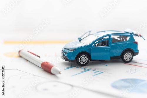 Small toy car and wooden toy house close up image on blueprint background.