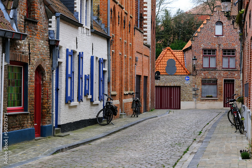 Romantic characteristic cobblestone alleyways streets and historic medieval brick old town houses in downtown Bruges, Belgium with canals, parks and skyline photo