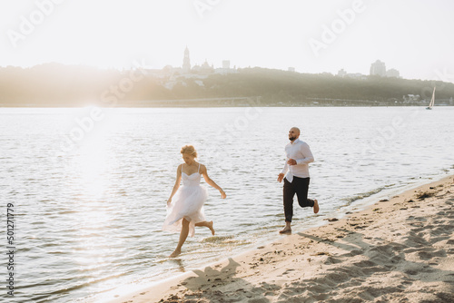 Wedding photosession at sunset of a beautiful couple  the bride in a white dress  and the groom in a white shirt and black trousers