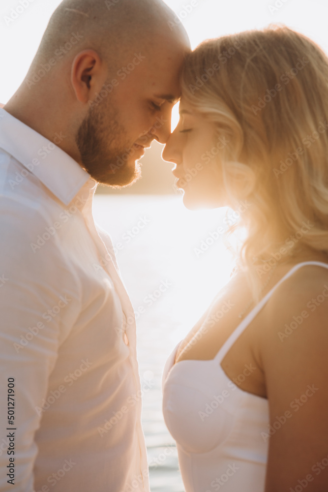 Wedding photosession at sunset of a beautiful couple, the bride in a white dress, and the groom in a white shirt and black trousers Wedding photosession at sunset of a beautiful couple, the bride in a white dress, and the groom in a white shirt and black trousers