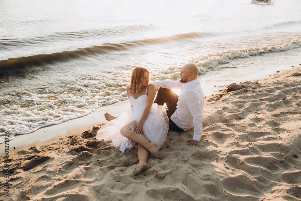 Wedding photosession at sunset of a beautiful couple, the bride in a white dress, and the groom in a white shirt and black trousers Wedding photosession at sunset of a beautiful couple, the bride in a white dress, and the groom in a white shirt and black trousers