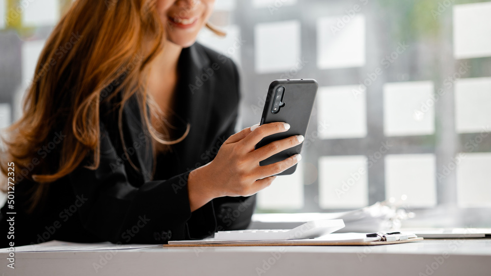 young businesswoman looking at financial information from a mobile phone, she is checking company financial documents, she is a female executive of a startup company. Concept of financial management. young businesswoman looking at financial information from a mobile phone, she is checking company financial documents, she is a female executive of a startup company. Concept of financial management.