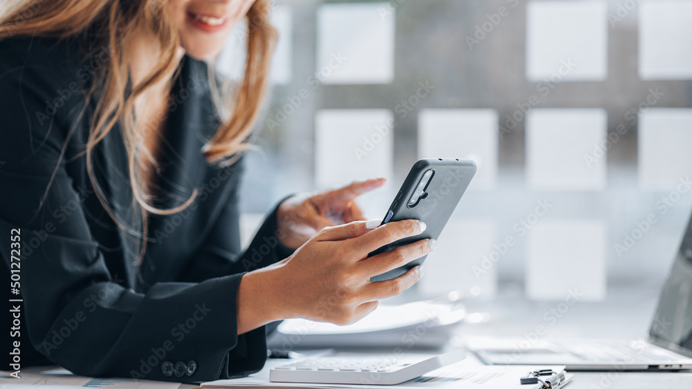 young businesswoman looking at financial information from a mobile phone, she is checking company financial documents, she is a female executive of a startup company. Concept of financial management. young businesswoman looking at financial information from a mobile phone, she is checking company financial documents, she is a female executive of a startup company. Concept of financial management.