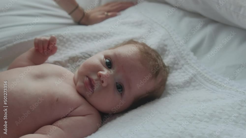 Portrait of a little newborn girl on a white sheet, taken in daylight. The child smiles and wonders Portrait of a little newborn girl on a white sheet, taken in daylight. The child smiles and wonders