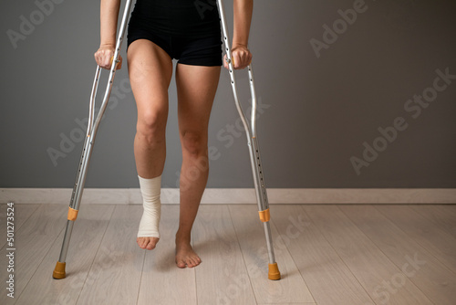 Photographie Front view close up of a disabled woman walking with crutches and sprained banda