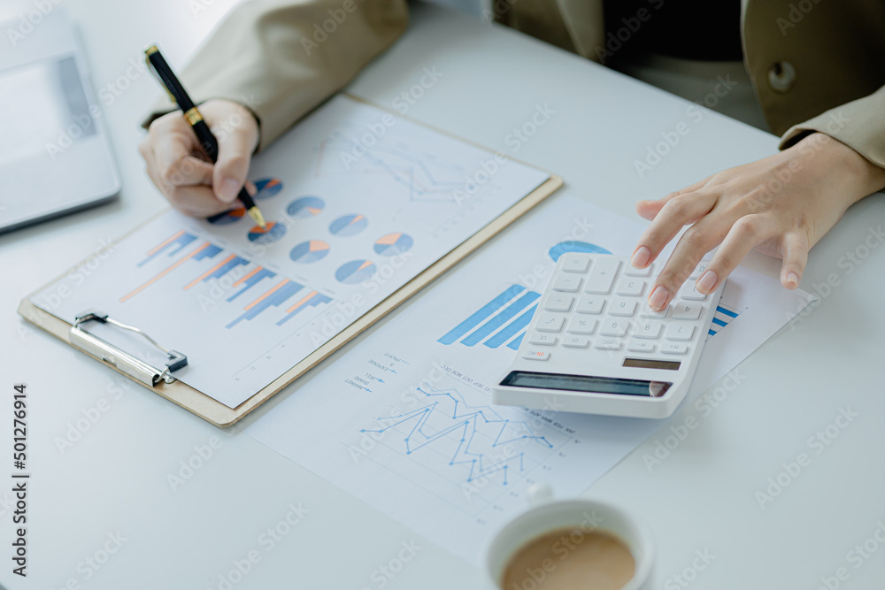 Businessman using a calculator to calculate numbers on a company's financial documents, he is analyzing historical financial data to plan how to grow the company. Financial concept. Businessman using a calculator to calculate numbers on a company's financial documents, he is analyzing historical financial data to plan how to grow the company. Financial concept.